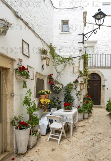 Narrow street with table and chairs in white town of Locorotondo, Apulia - Puglia, Italy