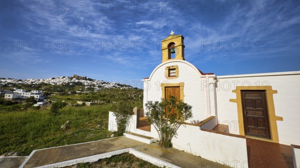 White chapel with wooden door and cross, surrounded by green nature, chapel south of the Chora, World Heritage Site 1999, Chora, Patmos, Dodecanese, Greek Islands, Greece