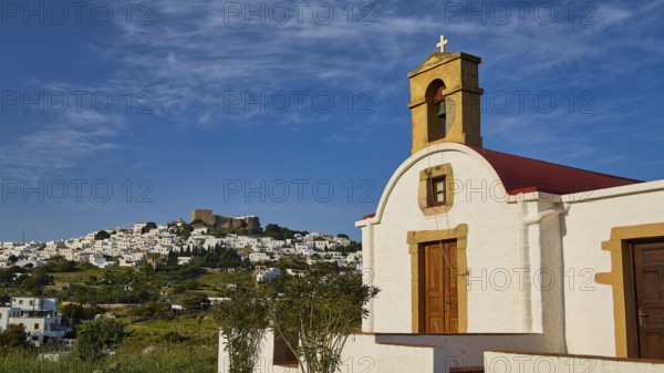 White chapel with cross and wooden door, village in the distance, chapel south of the Chora, World Heritage Site 1999, Chora, Patmos, Dodecanese, Greek Islands, Greece