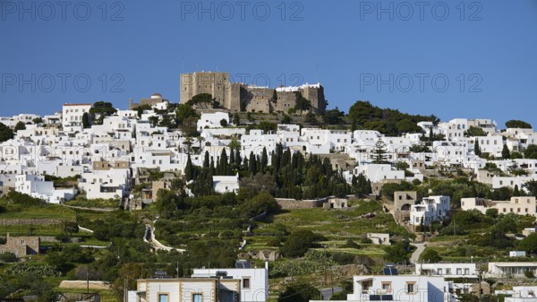 Whitewashed buildings on a green hill with an old castle in the background, Monastery of St John the Theologian, Monastery of St John the Theologian, World Heritage Site 1999, Chora, Patmos, Dodecanese, Greek Islands, Greece