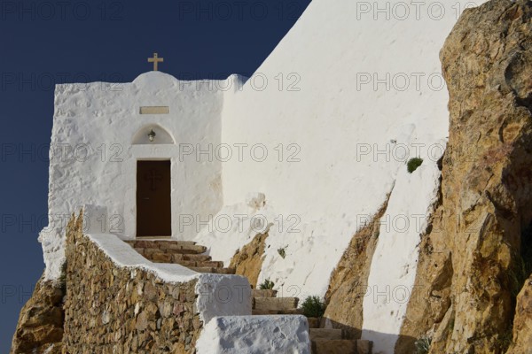 White church on rocky ground with stone steps and cross, under a blue sky, Church of the Prophet Elias, Profitis Ilias Chapel, Hermitage, Patmos, Dodecanese, Greek Islands, Greece