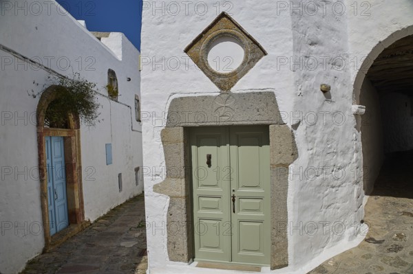 Green door with geometric frame in a white historic building with plants, Mantomata stones, Chora, UNESCO World Heritage Site 1999, Patmos, Dodecanese, Greek Islands, Greece