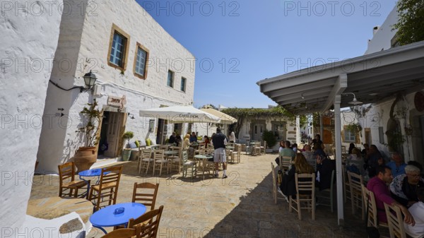Outdoor café with tables and chairs on a sunny terrace next to white houses, Platia Lesvias, Taverna Vangelis, Cafe Bar STOA, Chora, UNESCO World Heritage Site 1999, Patmos, Dodecanese, Greek Islands, Greece
