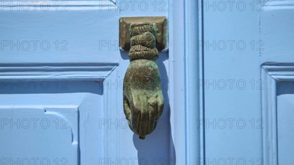 A metallic, hand-shaped door knocker on a blue door, depicted in detail, Chora, UNESCO World Heritage Site 1999, Patmos, Dodecanese, Greek Islands, Greece