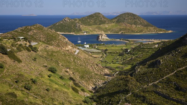 Hilly landscape with fields and coast, green and blue dominate the view, rocks of Kalikatsou, island of Tragonisi, Patoinos, organic viticulture, biodiversity garden, Patmos, Dodecanese, Greek Islands, Greece