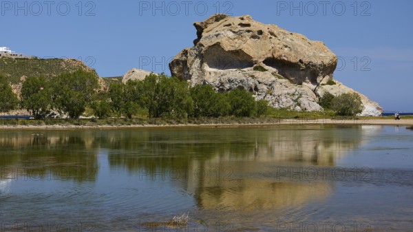 Elevated rock with its reflection in the calm lake on a sunny day, Seasonal salt lake, Rock of Kalikatsou, Patmos, Dodecanese, Greek Islands, Greece