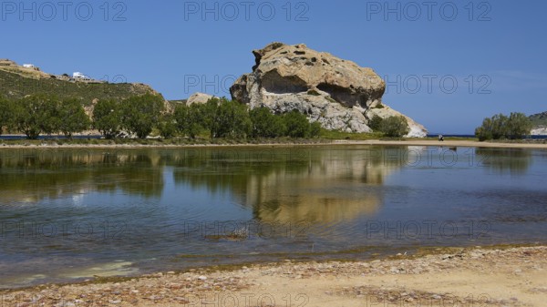 Large rock reflected in a calm lake under a blue sky, Rock of Kalikatsou, Seasonal Salt Lake, Patmos, Dodecanese, Greek Islands, Greece
