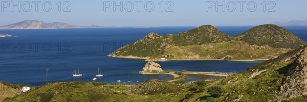 Panoramic view of sailing boats in front of mountains and a blue lake on an island, Rock of Kalikatsou, Seasonal Salt Lake, Tragonisi Island, Patmos, Dodecanese, Greek Islands, Greece