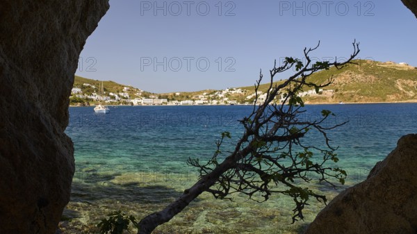 View through a rock opening over the blue sea and the coastal town, Cave, Grikos, Rock of Kalikatsou, Patmos, Dodecanese, Greek Islands, Greece