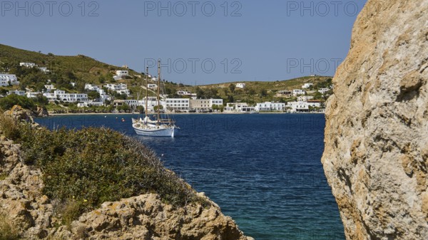 Sailing boat in a bay, surrounded by rocks and white buildings on the shore, Grikos, Rock of Kalikatsou, Patmos, Dodecanese, Greek Islands, Greece