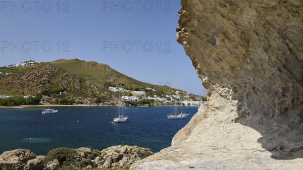 Several sailing boats on the sea, framed by rocks and white coastal town, Grikos, Petra, Chora, rocks of Kalikatsou, Patmos, Dodecanese, Greek Islands, Greece