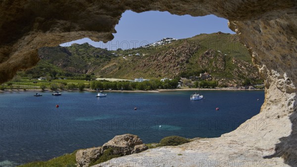 View from a cliff to the calm sea with boats and a green hilly coastal scene, cave, Chora, Grikos, Rock of Kalikatsou, Patmos, Dodecanese, Greek Islands, Greece