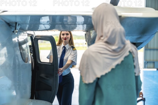 Female pilot welcoming a muslim passenger aboard a small airplane, embodying hospitality and inclusivity in aviation. Smiling and opening the door, creating a warm atmosphere for travel