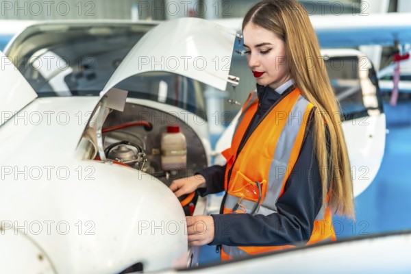 Aircraft maintenance engineer performing a pre flight inspection on a light aircraft engine in a hangar