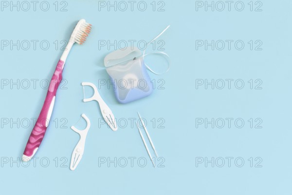 Dental floss, toothpicks and brush on side of blue background with copy space