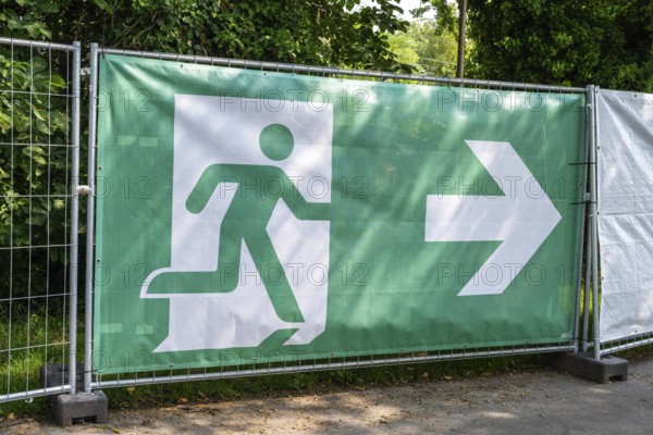 Bauzaun, Absperrung, Barriere mit einem Piktogramm einer flüchtenden Person, Symbos für Notausgang, Fluchtweg, Sicherheit bei Veranstaltungen wie Open-Air Konzerte bei großen Menschenansammlungen