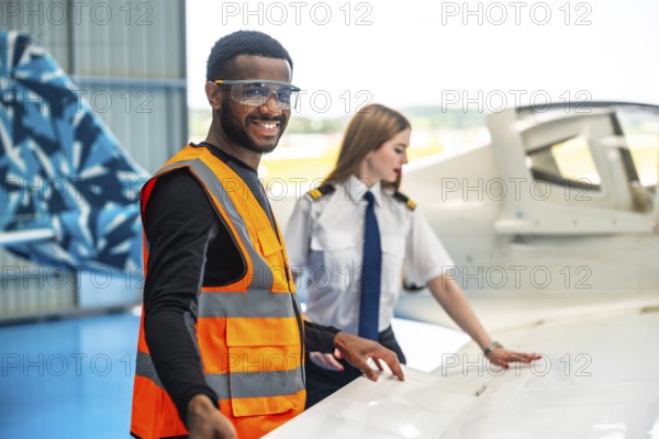 Smiling aircraft maintenance engineer and pilot inspecting airplane wing, ensuring safety and optimal performance before flight
