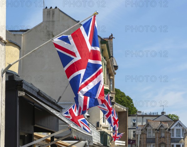 Union Jack flags on shops in street of historic buildings, The Strand, Dawlish, south Devon, England, UK