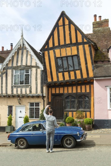 Person taking phone photo of The Crooked House, Lavenham, Suffolk, England, UK
