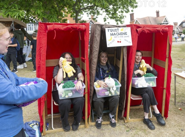 Three women forming human fruit machine game at village summer fete, Bawdsey, Suffolk, England, UK