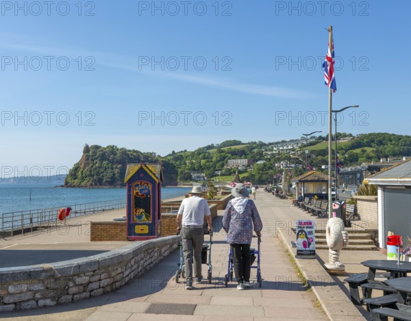 Two elderly people walking with rollators, Seafront promenade view west towards Teignmouth, south Devon, England, UK