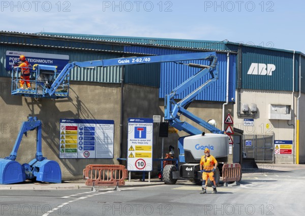 Man on cherry picker machinery cleaning sign, Port of Teignmouth, Teignmouth, south Devon, England, UK