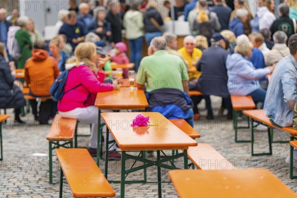 Outdoor event with beer tables and guests, one table is decorated with a pink flower, family party in Neubulach, district of Calw, Germany