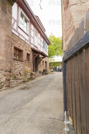 Narrow alley with traditional half-timbered houses and stone walls in a historic neighbourhood, family festival in Neubulach, district of Calw, Germany