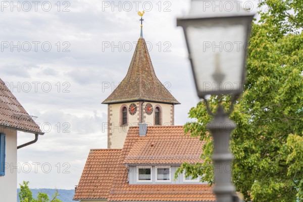 Idyllic view of a church tower with weathercock in the village with blue sky and clouds, family celebration in Neubulach, district of Calw, Germany