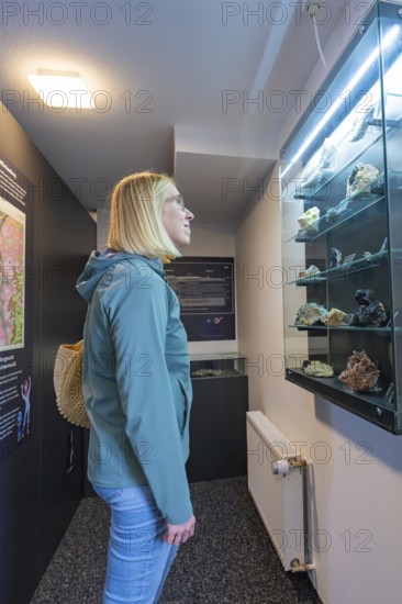 Woman looking with interest at a display case with stones in a museum, family festival in Neubulach, district of Calw, Germany