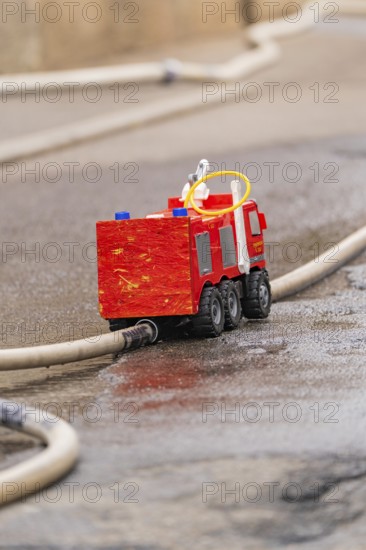 Small red toy fire engine examined on a wet road, family party in Neubulach, Calw district, Germany