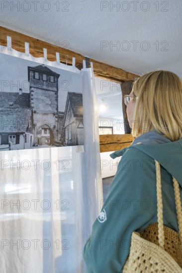 Woman looking at historical photograph in a room with wooden elements, family celebration in Neubulach, district of Calw, Germany