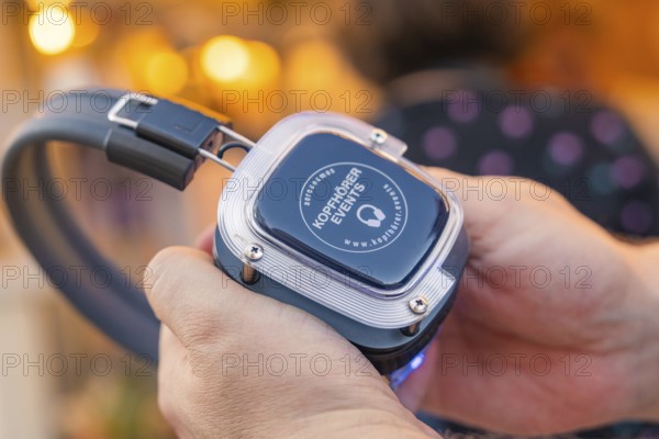 Advanced headphones are held in one hand and looked at, Calw railway station festival, Black Forest, Germany