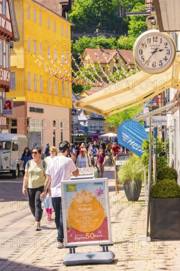 Lively shopping street with cheerful passers-by and colourful decorations on a sunny day, Calw station festival, Black Forest, Germany