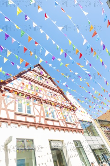 Colourful half-timbered house with flags under a bright blue sky, Calw station festival, Black Forest, Germany