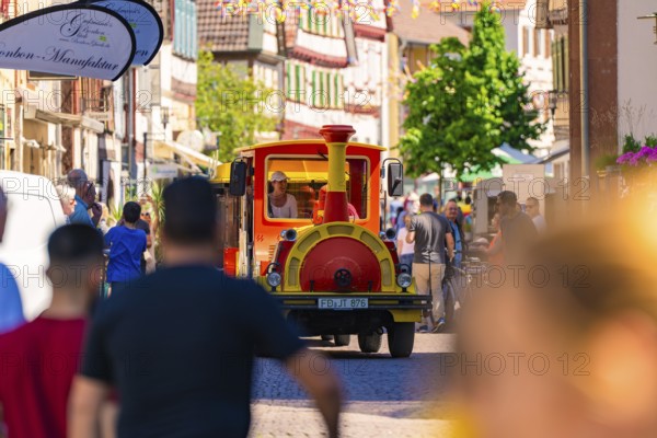Tourist train runs through a lively, sunny city street, Calw railway station festival, Black Forest, Germany