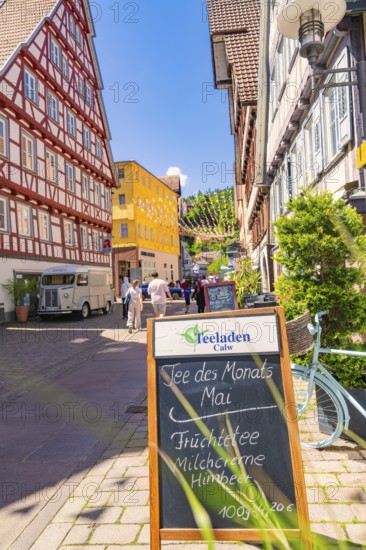 Half-timbered house street with board and bicycle in the foreground, sunny cityscape, Calw railway station festival, Black Forest, Germany