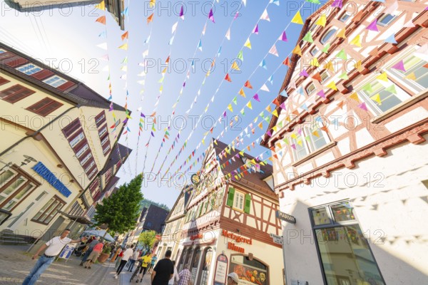 Colourful pennants span a picturesque street with half-timbered houses, Calw station festival, Black Forest, Germany