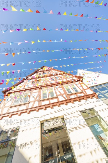 Half-timbered house decorated with colourful pennants under a clear blue sky, Calw station festival, Black Forest, Germany
