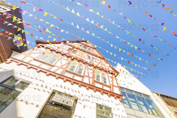 Medieval half-timbered house with colourful pennants in front of a blue sky, Calw station festival, Black Forest, Germany