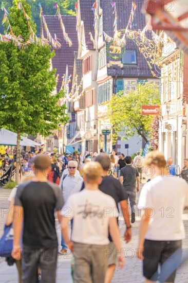 Lively city street with people and sun in summer, Calw railway station festival, Black Forest, Germany
