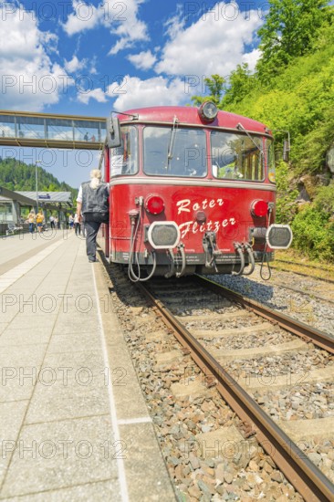 Travellers boarding a red train in the sunshine, Calw station festival, Black Forest, Germany