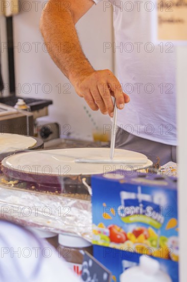 Person preparing crepe batter at a market stall, Calw railway station festival, Black Forest, Germany