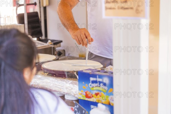 Man preparing crepes in a market stall with Capri-Sun in the background, Calw railway station festival, Black Forest, Germany