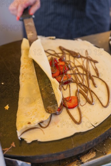A crêpe is topped with chocolate and strawberries and rolled up, Calw railway station festival, Black Forest, Germany