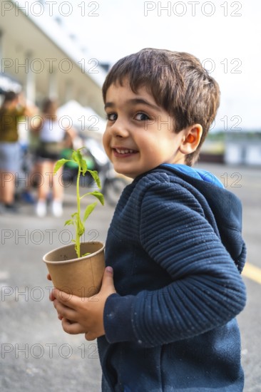 Young boy holding a small plant in a biodegradable pot, symbolizing environmental protection and sustainability