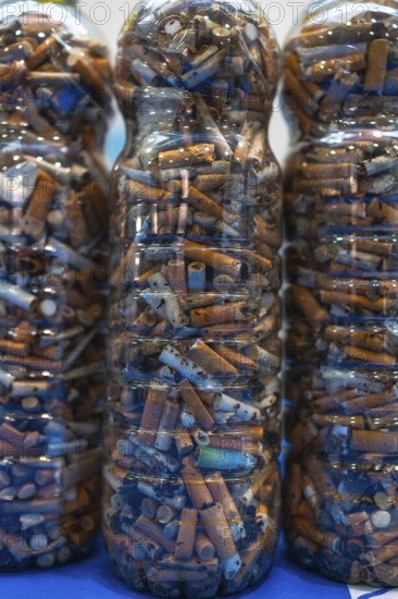 Plastic bottles filled with cigarette butts collected during cleanup efforts on a beach, highlighting environmental pollution and smoking hazards