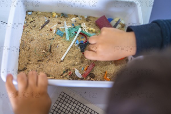 Young student analyzing a sand sample containing microplastics, highlighting the growing concern of plastic pollution in marine environments