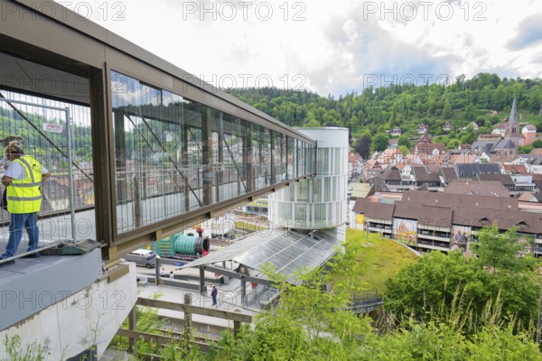 People standing on a modern bridge with a view of a hilly urban landscape, Zob extension with bridge construction for the new Herman Hesse railway, Calw, Black Forest, Germany