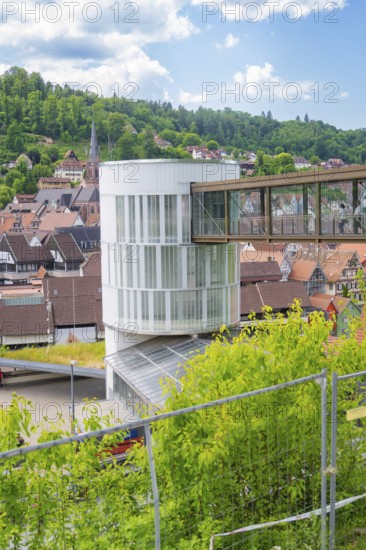 A modern building with a bridge in a town surrounded by green landscape and houses, Zob extension with bridge construction for the new Herman Hesse railway, Calw, Black Forest, Germany